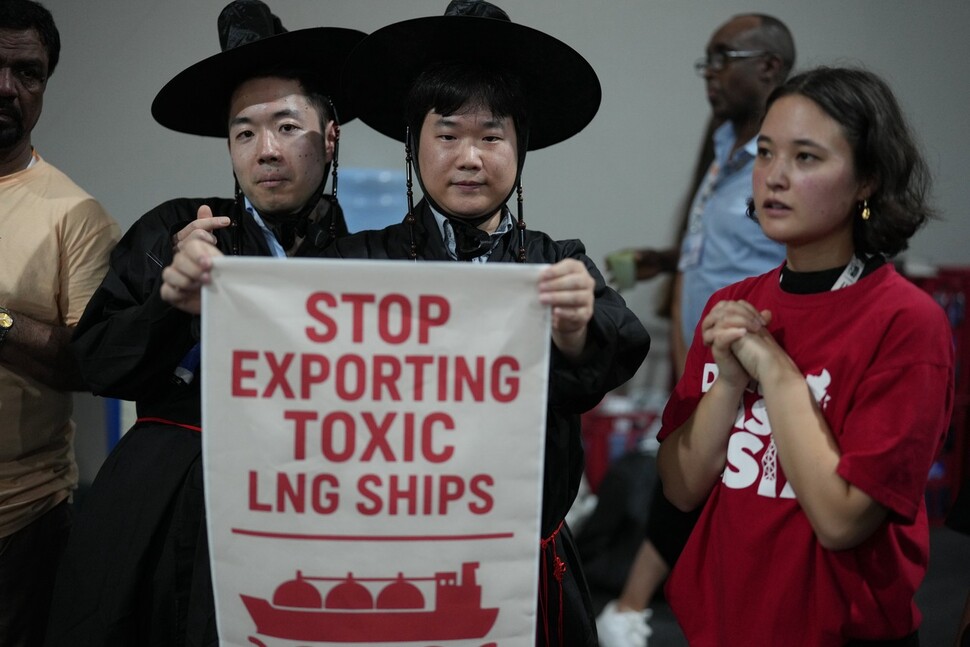 지난 17일(현지시각)에 브라질 벨렝에서 아시아 지역 환경단체 활동가들이 ‘유독성 액화천연가스(LNG) 선박 수출을 중단하라’는 문구가 적힌 팻말을 들고 있다. 벨렝/AP 연합뉴스