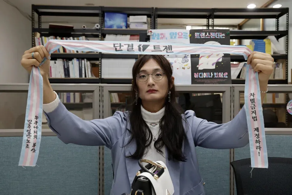 On April 14, 2025, Cho Yong-hwa, a trans woman who works as a researcher at a labor institute in Jeolla associated with the Korean Confederation of Trade Unions, holds up a labor headband made of the transgender pride flag colors. (Kim Myoung-jin/Hankyoreh)