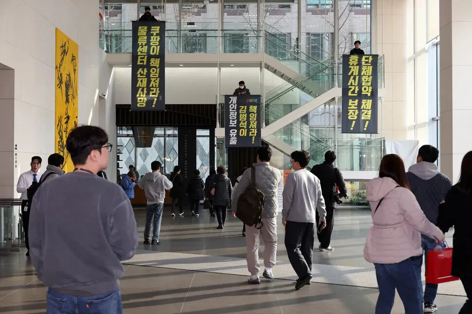 Members of the Coupang distribution center union unfurl large banners reading “Coupang must take responsibility for industrial accident deaths at its distribution centers!” “Kim Bom-suk must take responsibility for the leaking of customers’ personal information!” and “Sign the collective agreement! Guarantee break time!” during a surprise demonstration at the e-commerce giant’s headquarters in Seoul’s Songpa District on Dec. 10, 2025. (Kim Young-won/Hankyoreh)