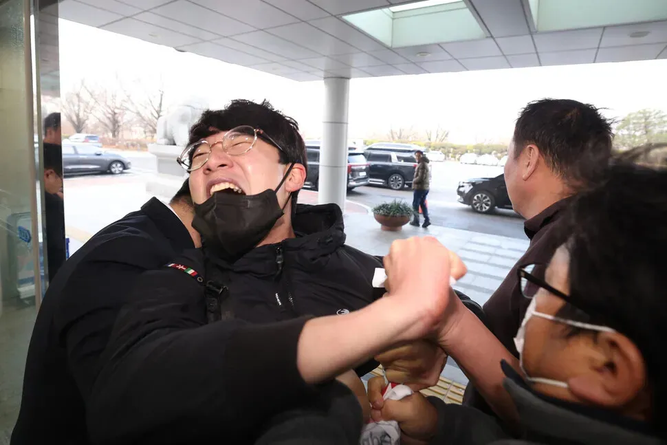 Unionists are restrained after protesting Harold Rogers, the new interim CEO of e-commerce giant Coupang, as he arrives at the National Assembly on Dec. 17, 2025, for a hearing on the company’s data breach. (Choi Hyeon-su/Hankyoreh)