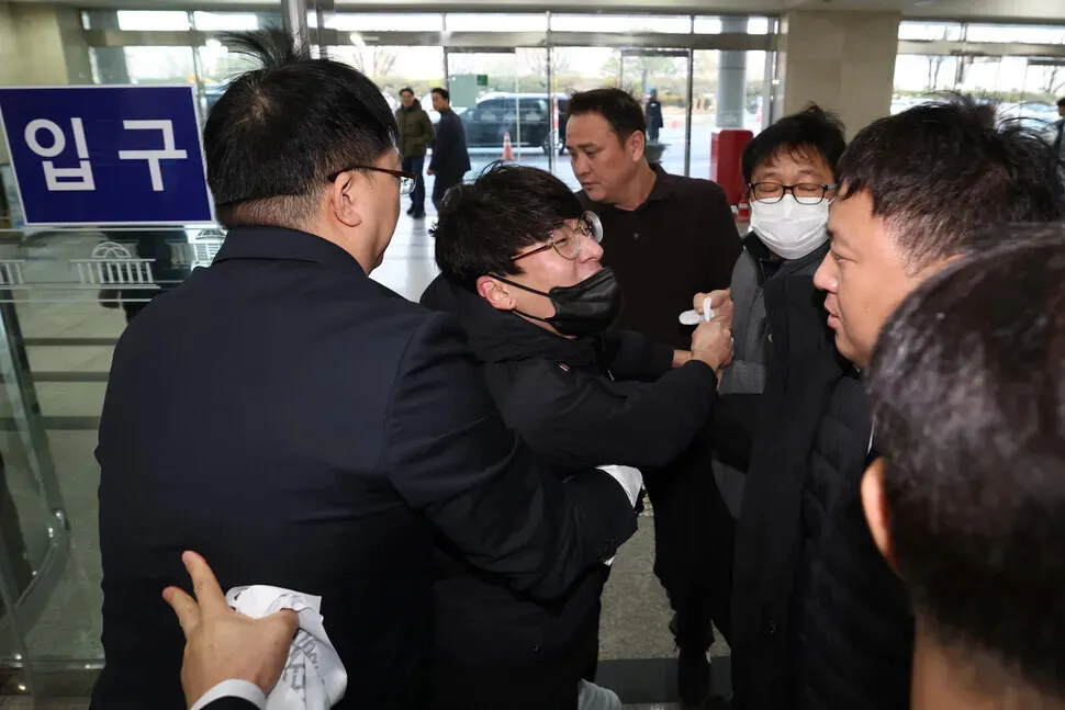 Unionists are restrained after protesting Harold Rogers, the new interim CEO of e-commerce giant Coupang, as he arrives at the National Assembly on Dec. 17, 2025, for a hearing on the company’s data breach. (Choi Hyeon-su/Hankyoreh)
