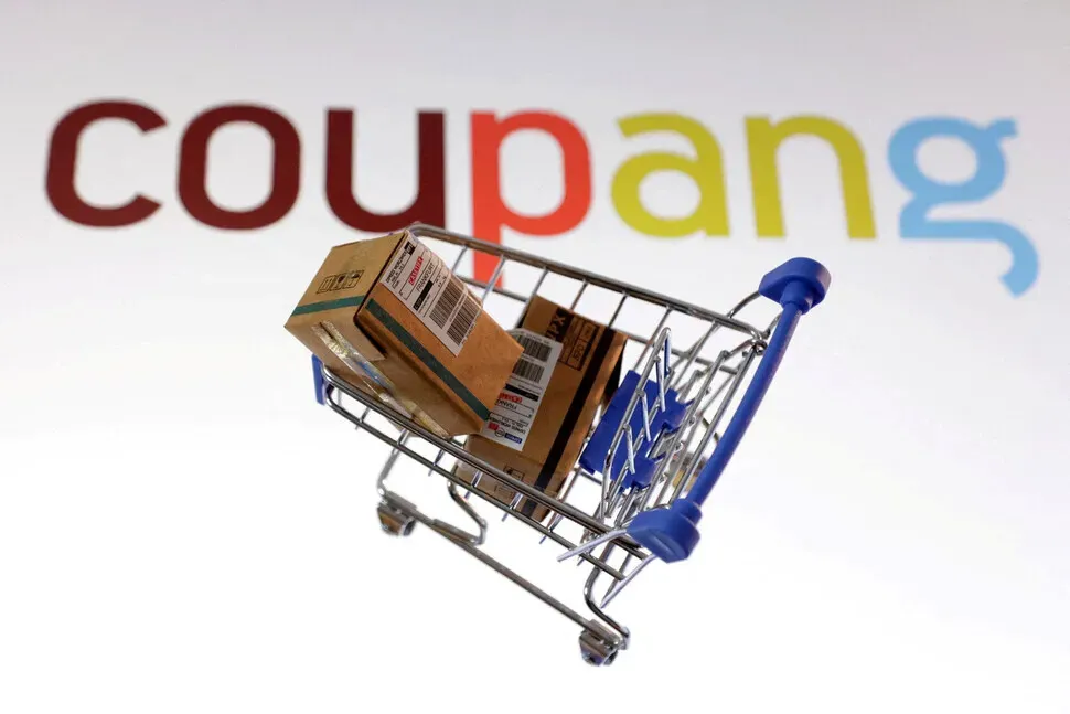 A model of a shopping cart filled with packages with the Coupang logo in the background. (Reuters/Yonhap)