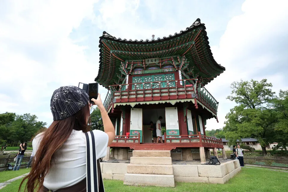A palace-goer snaps a picture of Gyeongbok Palace’s Hyangwon Pavilion on Sept. 2, 2026. (Choi Hyeon-su/Hankyoreh)