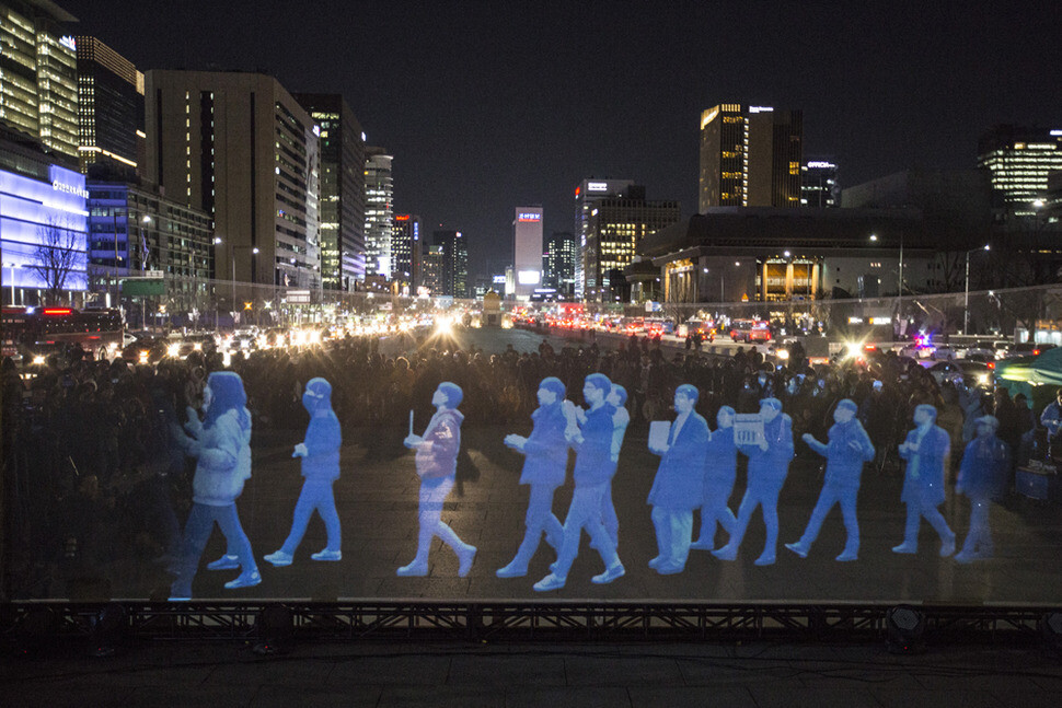 Hologram images of marchers move across a screen in front of Gwanghwamun Gate in Seoul during a ‘Ghost Protest’ organized by the South Korea branch of Amnesty International calling for freedom of assembly