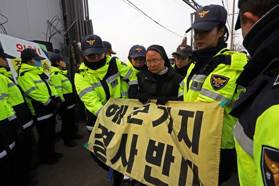 Police move participants in a mass at the entrance to the construction site of a naval base in Gangjeong Village