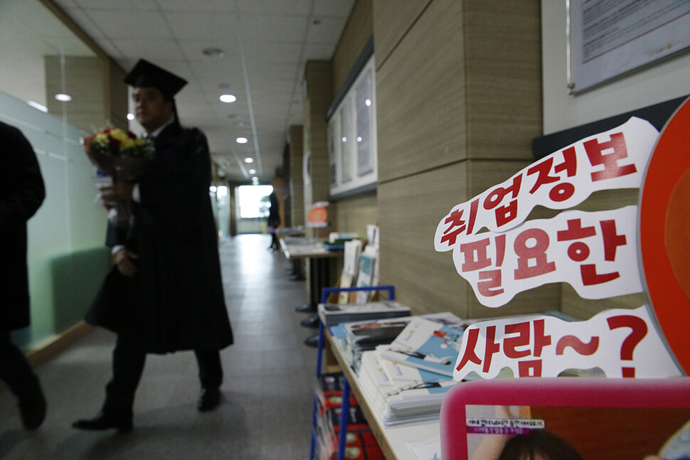 A graduate at Dongguk University in Seoul passes by an employment information pamphlets