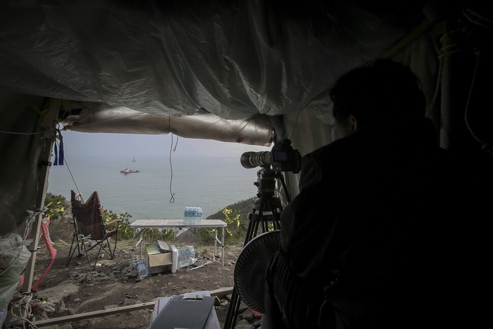 세월호 인양 감시를 위해 전남 진도군 동거차도 꼭대기에 움막을 짓고 생활하는 유족들이 지난 3월7일 오후 인양 사전 작업을 카메라에 담고 있다.