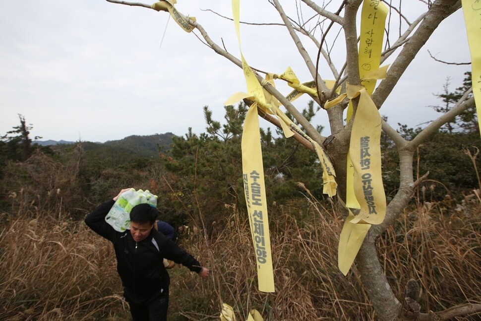 세월호 참사로 아들 정수를 잃은 최태신씨가 산마루 감시초소로 짐을 지고 오르고 있다.