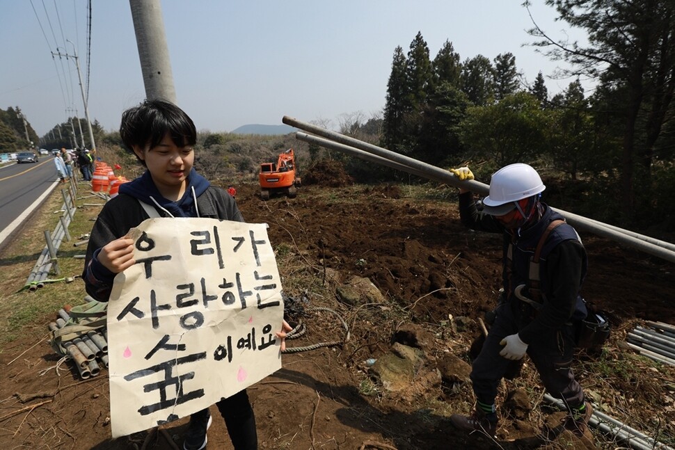 한 시민이 비자림로 확장 공사 현장 주변에서 손팻말을 든 채 공사 중단을 호소하고 있다.