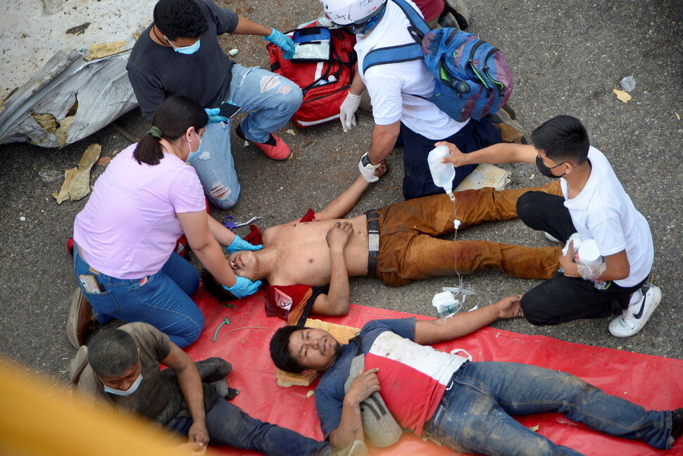 멕시코 구급대원들이 치아파스주 툭스틀라 구티에레스에서 발생한 이민자 수송 화물트럭 전복사고 현장에서 부상자들을 치료하고 있다. 툭스틀라 구티에레스/로이터 연합뉴스