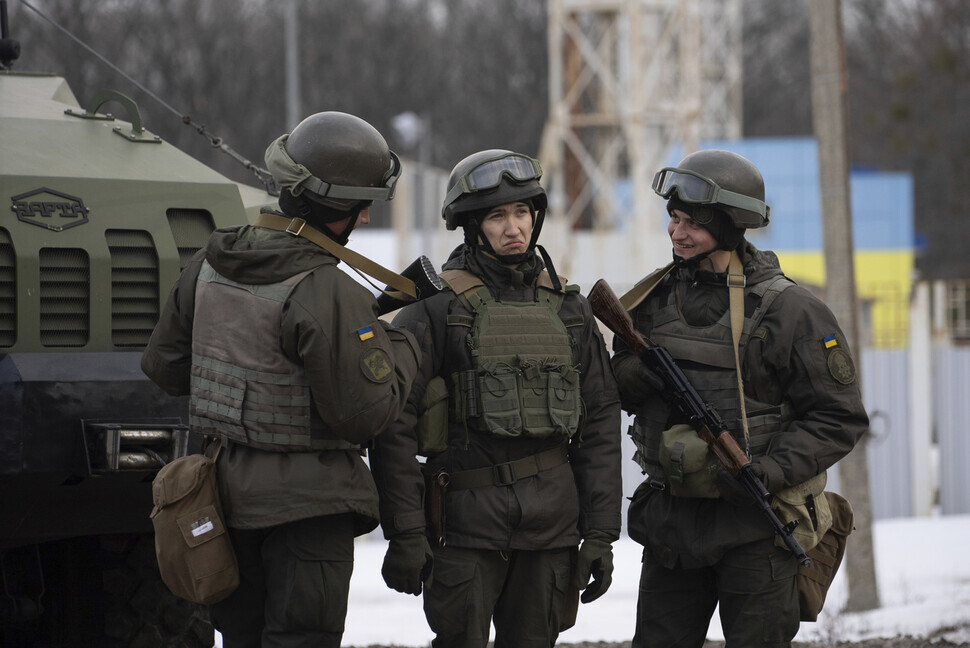Members of Ukraine’s state military chat outside the Kharkiv checkpoint near the country’s northeastern border. (AP/Yonhap News)
