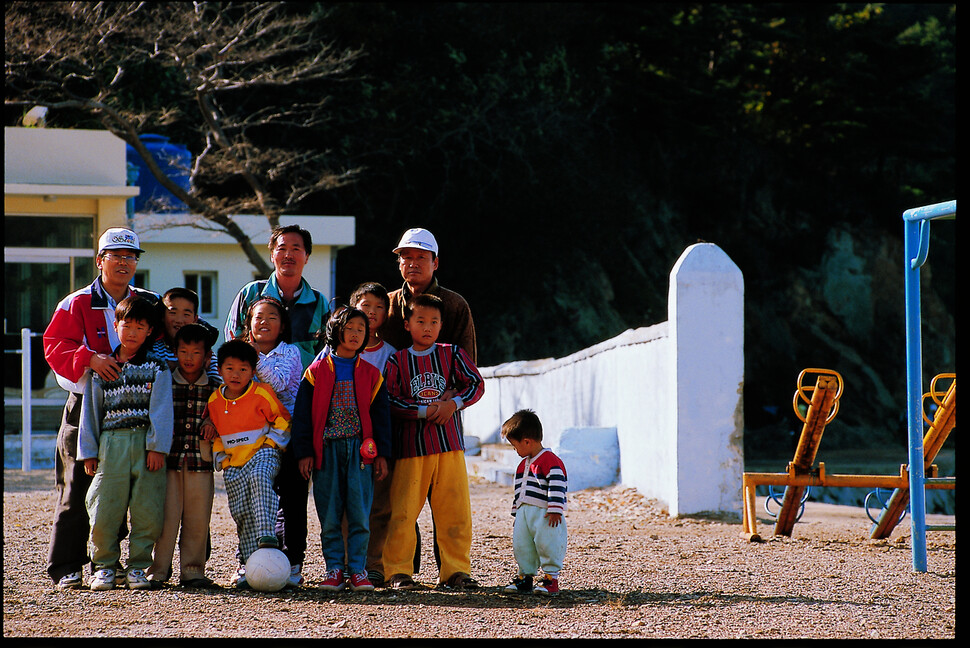 1997년 3월 인천 남부초등학교 이작분교 전교생 8명이 학교 운동장에서 교직원과 함께 찍은 사진. 맨 오른쪽은 형을 따라 등교한 김민욱(당시 4살)씨. 김씨는 사진 속 학생들이 모두 떠난 대이작도에 홀로 남아 섬을 지키고 있다.