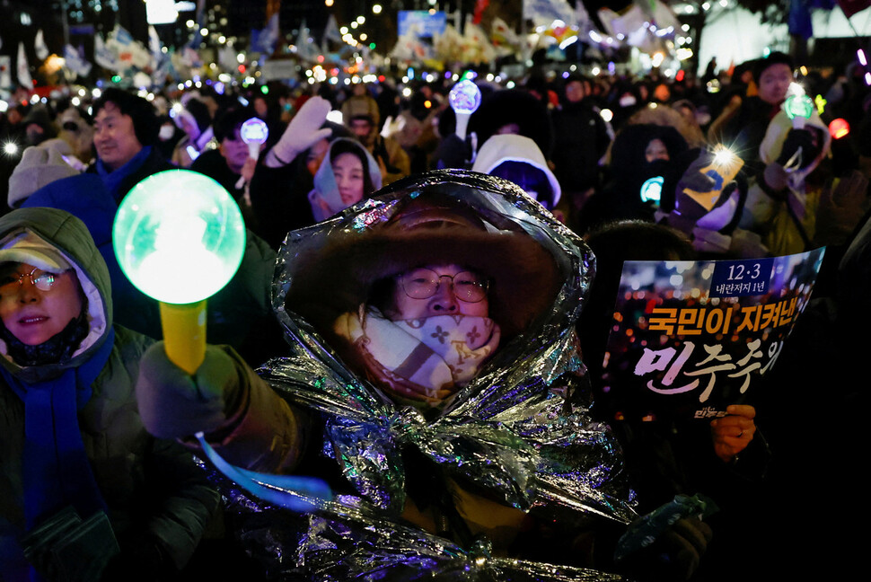 은빛 방한포를 몸에 두른 시민이 12월3일 저녁 국회 앞에서 열린 집회에 참석해 구호를 외치고 있다. REUTERS