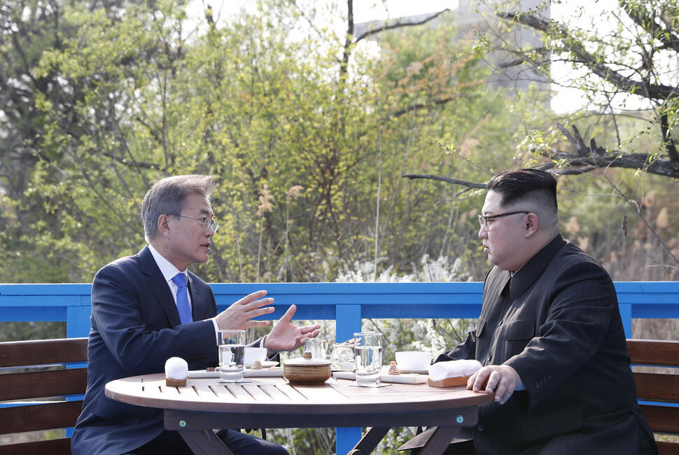 President Moon Jae-in speaks to North Korean leader Kim Jong-un on a bench at the far end of a pedestrian bridge in Panmunjeom during their summit on Apr. 27. (Photo Pool)