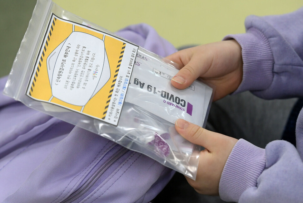 A student at one preschool in Seoul’s Guro District holds up a rapid antigen COVID-19 test kit that was passed out by their teacher on Tuesday. (pool photo)
