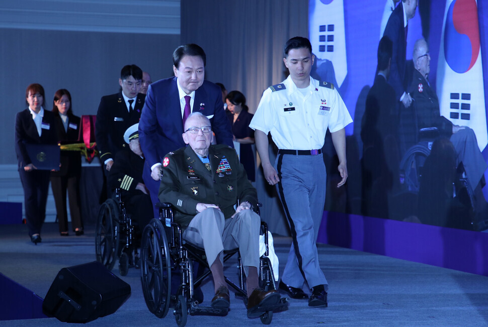 President Yoon Suk-yeol of South Korea escorts retired Army Col. Ralph Puckett across the stage at a luncheon celebrating the 70th anniversary of the South Korea-US alliance held at a hotel in Washington on April 25. (Yoon Woon-sik/The Hankyoreh)