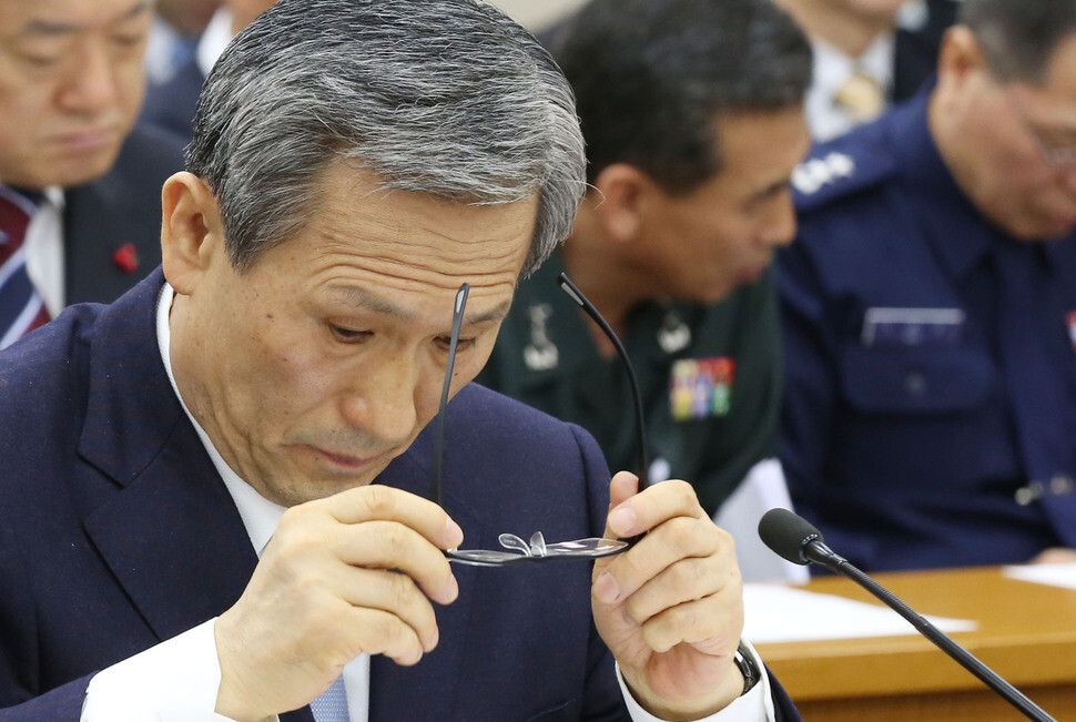 Former Defense Minister Kim Kwan-jin pauses to look at documents while answering questions about the results of an investigation into the Military Cyber Command’s online commenting activities at a hearing of the National Assembly Defense Committee on Dec. 23