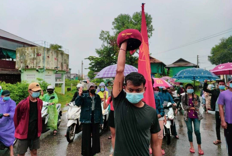 2021년 5월30일 미얀마 남부 도시 다웨이에서 청년들이 빗속에서 “군부독재 타도”를 외치고 있다. 국민통합정부(NUG) 깃발 앞에 선 청년(가운데)은 저항을 상징하는 ‘발우’(스님이 공양할 때 쓰는 그릇)를 치켜들고 있다. <미얀마 투데이> 페이스북 갈무리