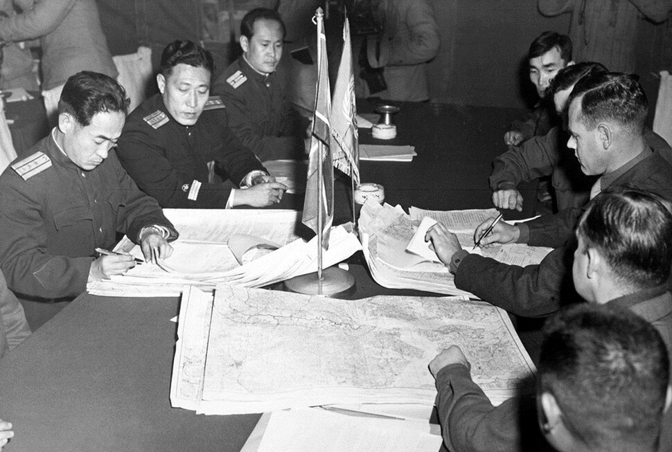 1951년 10월11일 판문점에서 열린 정전회담에서 유엔군의 머리 대령(오른쪽 가운데)과 북한 인민군의 장춘산 대령(맨 왼쪽)이 비무장지대에 남북군사분계선이 그려진 지도를 보며 가조인하고 있다.