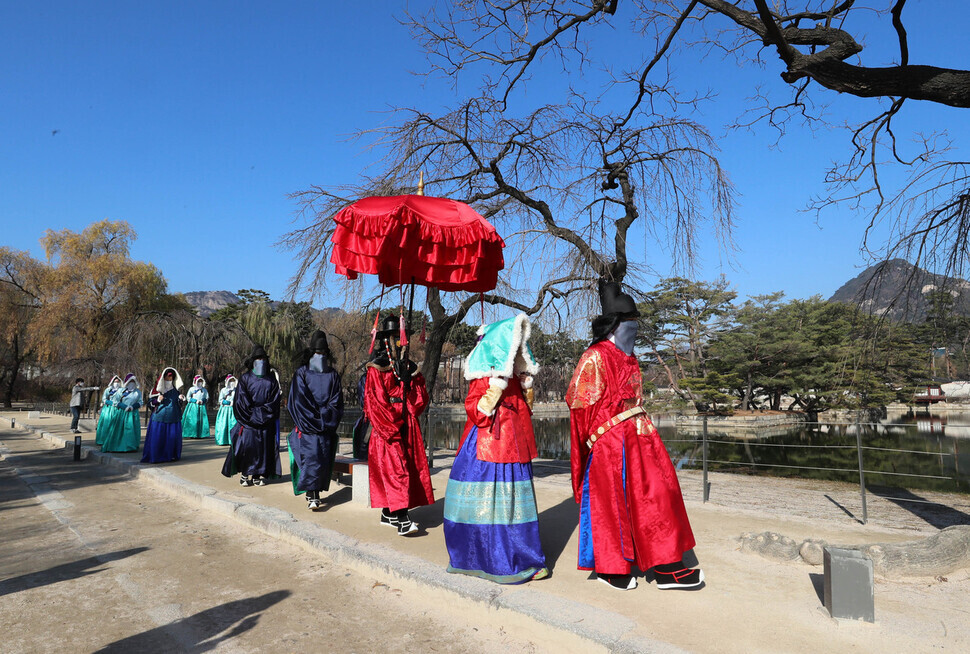 Kicking off the royal family walk event at Gyeongbok Palace on Wednesday morning, actors dressed in Joseon-era garb make their way around Gyeonghoeru Pavilion. (Shin So-young/The Hankyoreh) 
