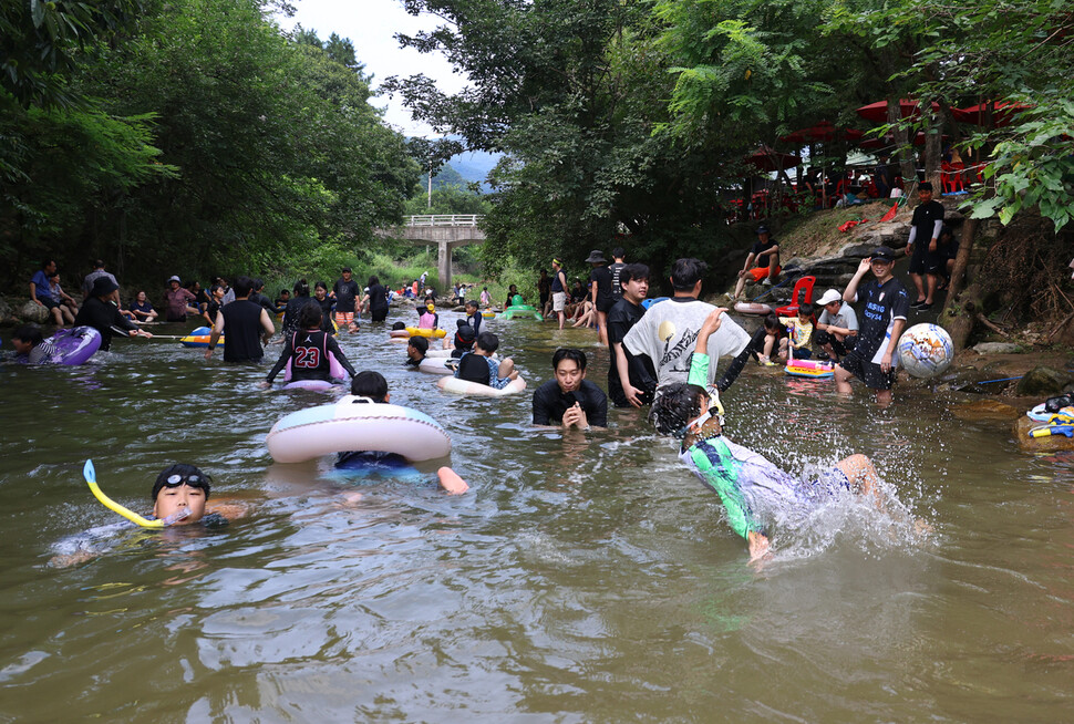 2025년 8월 첫째 주말인 2일 경기도 양평군 옥천면 신복천에서 오윤상(앞줄 오른쪽)군이 물속에서 공중제비를 돌며 공을 차고 있다. 뒤쪽에서 시민들이 아이들과 어울려 놀고 있다.