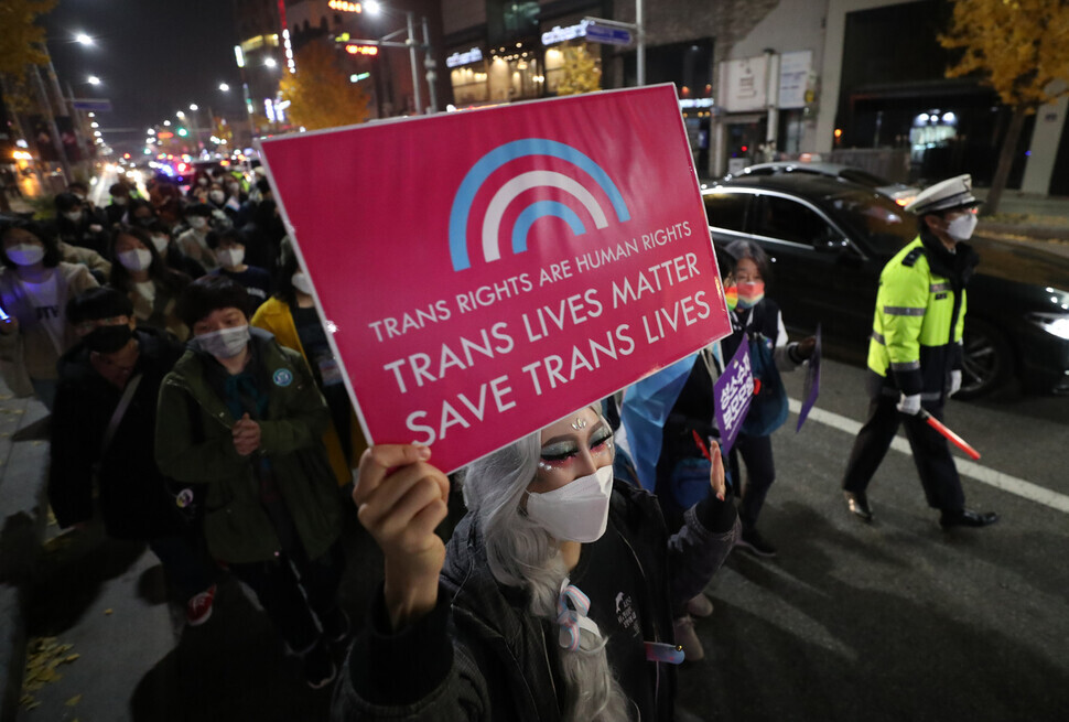 One attendee holds up a sign reading “Trans lives matter” while marching down a street in Itaewon. (Kang Chang-kwang/The Hankyoreh)