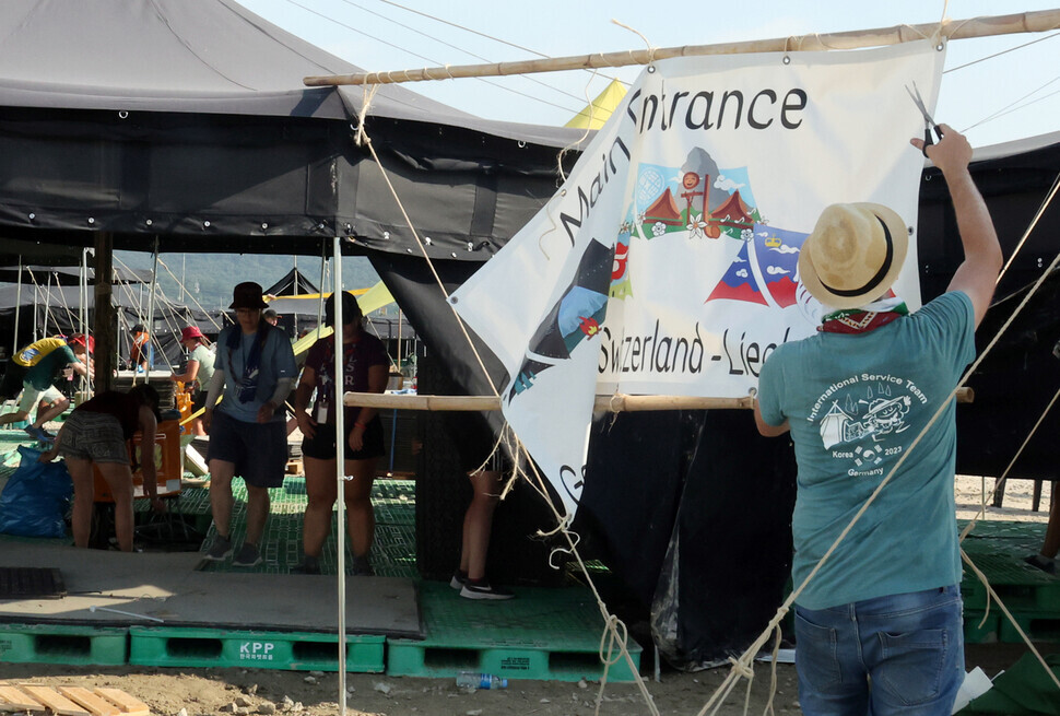 A participant in the jamboree tears down a banner at the Saemangeum campsite on Aug. 7, the day that it was announced all participants would be moved from the camp early due to the incoming typhoon. (Yonhap)