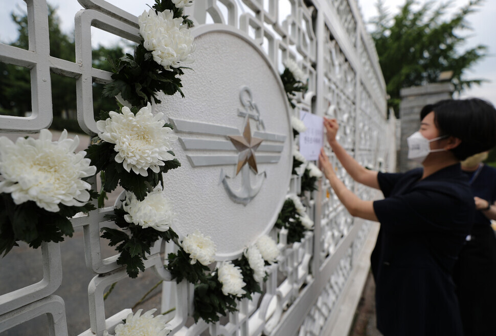 A woman puts up signs and flowers on the gate of the Ministry of National Defense in Seoul on June 10 to commemorate the Air Force master sergeant who died by suicide in June after being sexually assaulted. (Lee Jong-keun/The Hankyoreh)