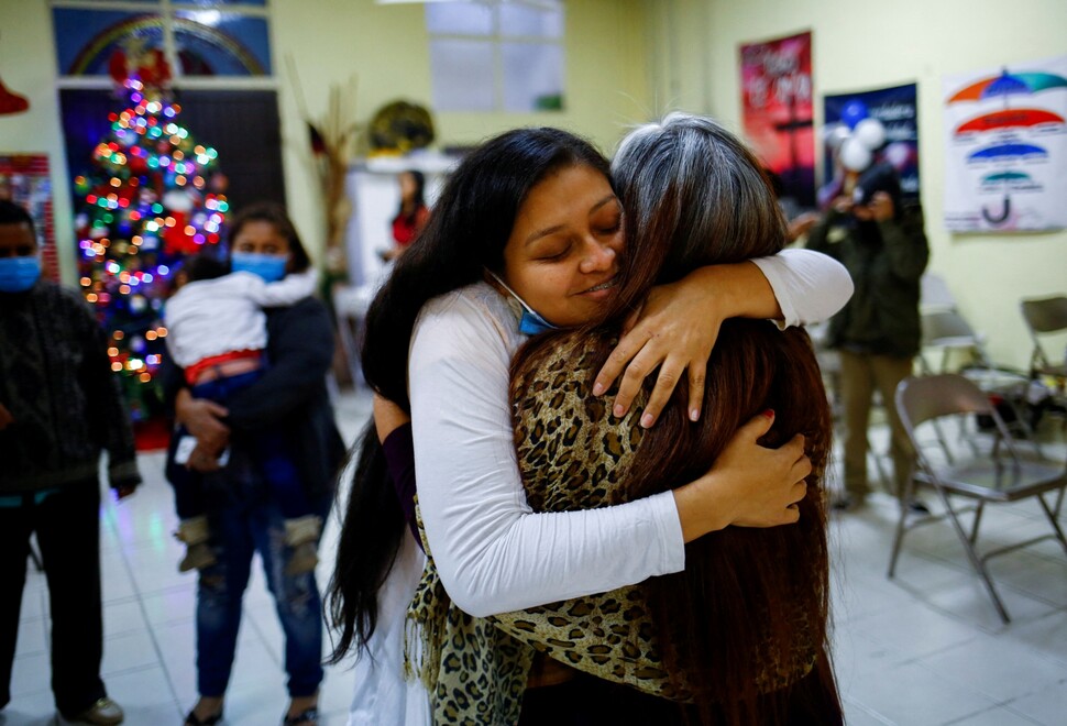 폭력을 피해 고향을 떠난 이주민 아델리네 시리아코가 멕시코 시우다드후아레스의 쉼터에서 새해를 축하하며 관리자를 끌어안고 있다.