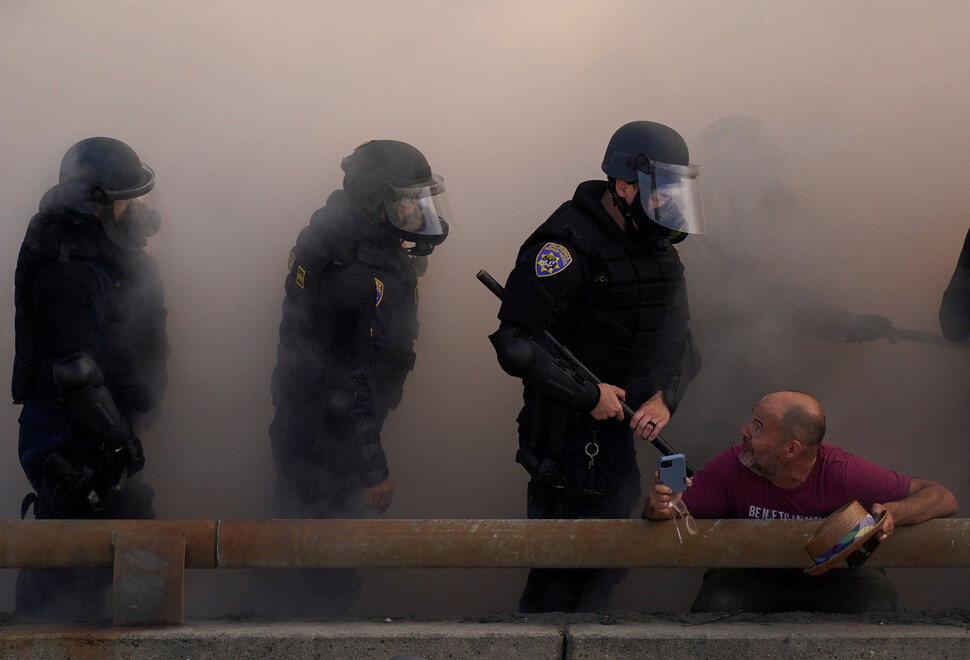 2025년 6월8일 최루탄 연기로 가득 찬 미국 캘리포니아주 로스앤젤레스에서 곤봉을 든 진압경찰이 시위대 해산 작전을 벌이고 있다. REUTERS 연합뉴스