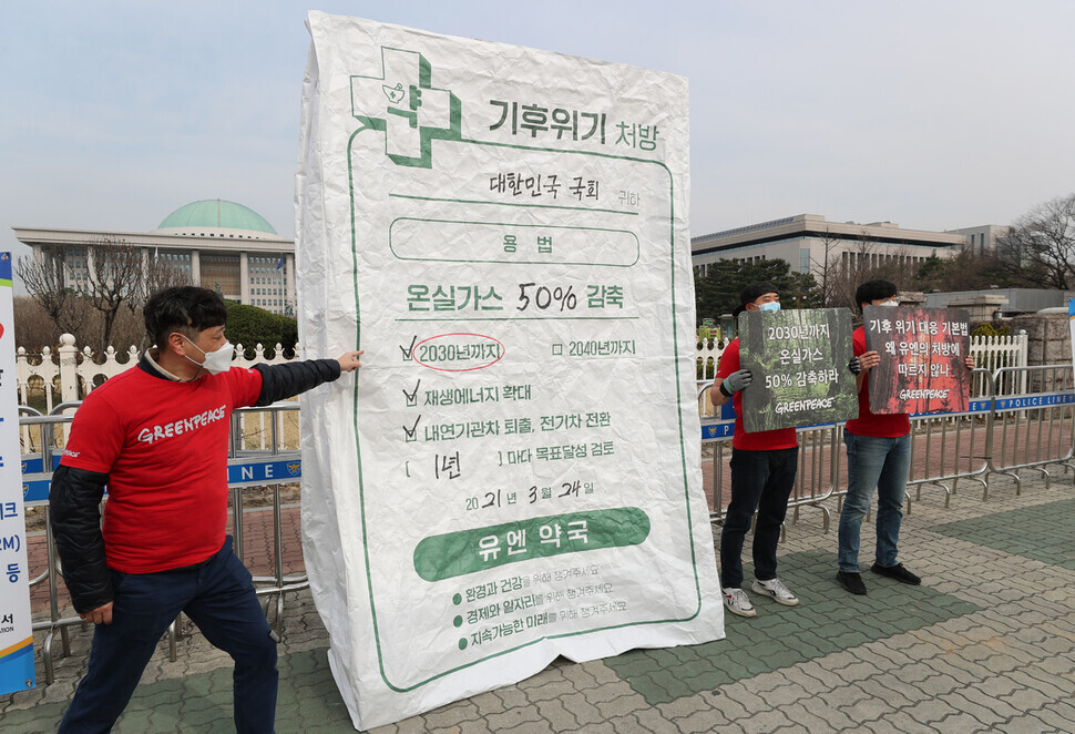 Members of Greenpeace hold a protest Wednesday in front of the National Assembly criticizing its recent climate change bills for their omission of a definite greenhouse gas reduction goal. (Kang Chang-kwang/The Hankyoreh)