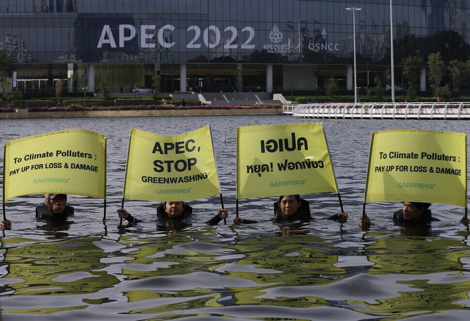 Greenpeace Thailand activists hold up signs as they stand in water outside the location of the APEC summit in Bangkok on Nov. 18-19. (EPA/Yonhap)
