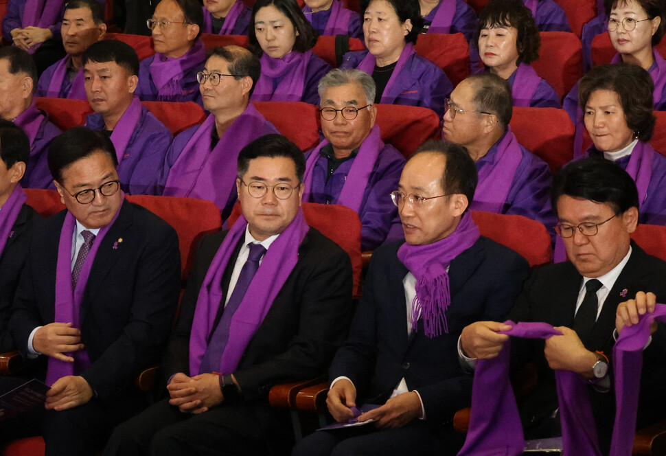 추경호 국민의힘 원내대표(앞줄 오른쪽 둘째)가 참석자들과 다른 방식으로 목도리를 맨 채 앉아 있다. 우원식 국회의장이 추 원내대표 쪽을 바라본다.