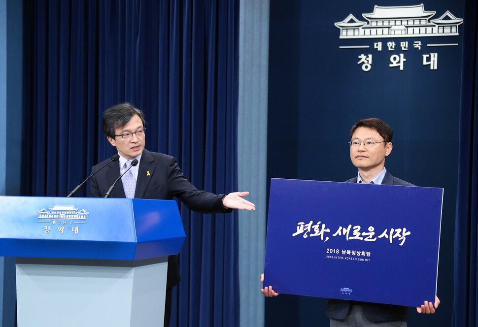 Blue House spokesman Kim Eui-kyum gestures to a sign displaying the official slogan