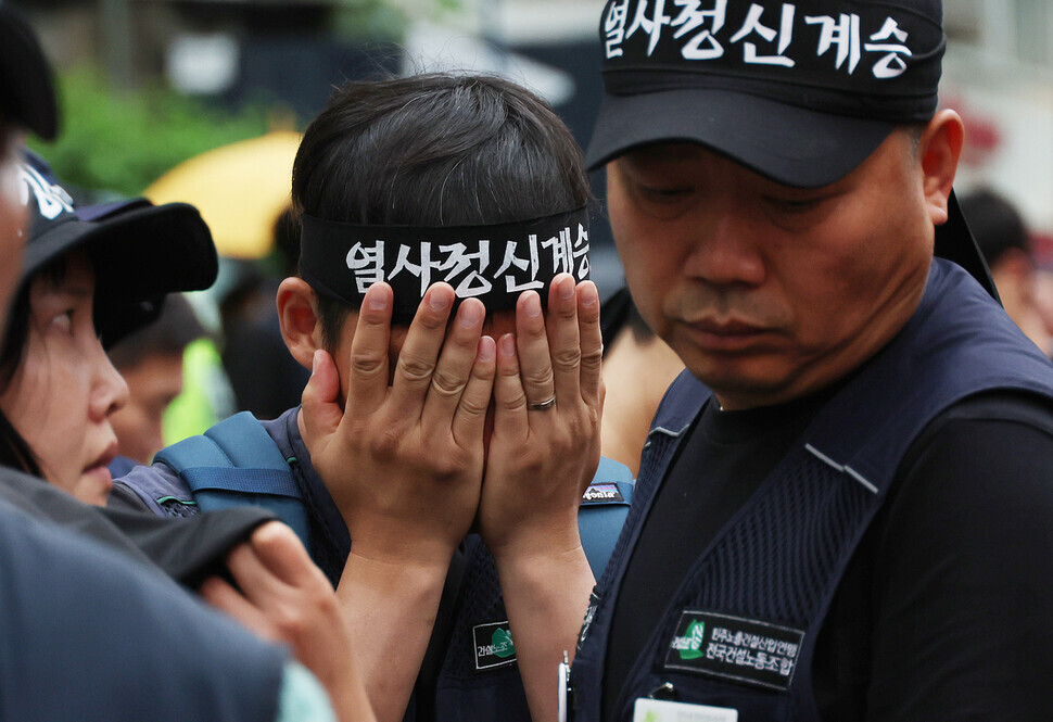 A unionist participating in a funeral march for Yang Hoe-dong, who self-immolated on May Day, covers their face with their hands as the rally carries Yang’s remains on June 21. (Shin So-young/The Hankyoreh)
