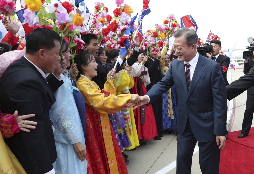 문재인 대통령이 평양 순안공항에 환영 나온 북한 시민들에게 다가가 손을 잡고 있다.