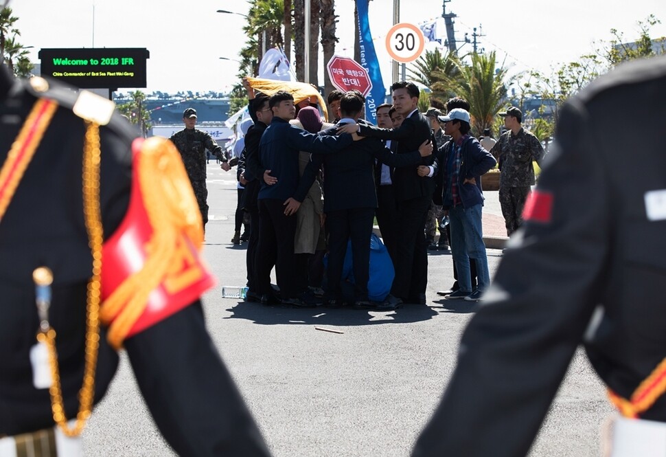 로널드 레이건호 입항에 항의해 해군기지 정문 안으로 들어간 지킴이들이 신분을 밝히지 않은 양복 입은 사람들에게 둘러싸여 있다.