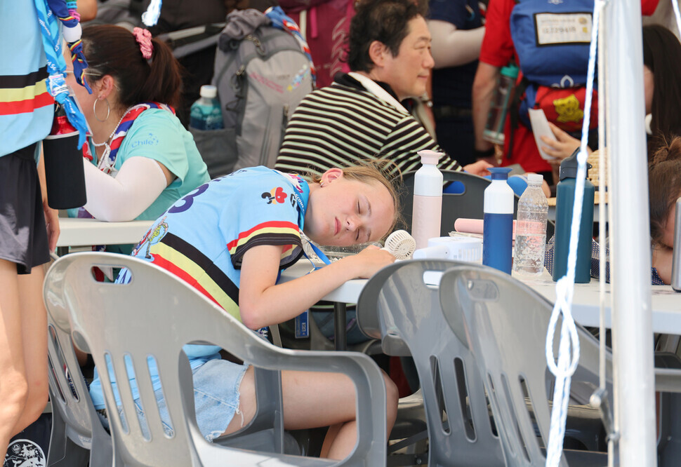 A scout taking part in the 2023 World Scout Jamboree seeks relief from the heat in a tent at the campsite in Saemangeum, North Jeolla Province, on Aug. 3. (Yonhap)