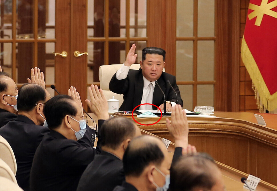 Those present at the Politburo meeting appear to be wearing masks, while the mask worn by Kim Jong-un sits on the desk in front of him. (Korean Central Television/Yonhap News)