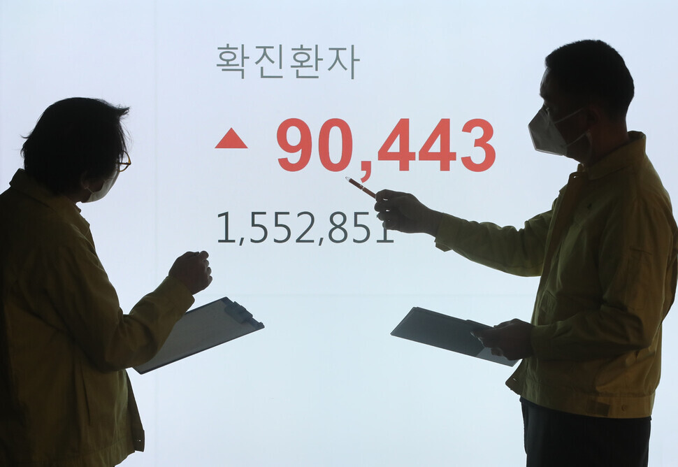 Staff at the Songpa District Office in Seoul stand in front of a monitor that displays the record-shattering number of new COVID-19 cases announced on Wednesday. (Kim Tae-hyeong/The Hankyoreh)
