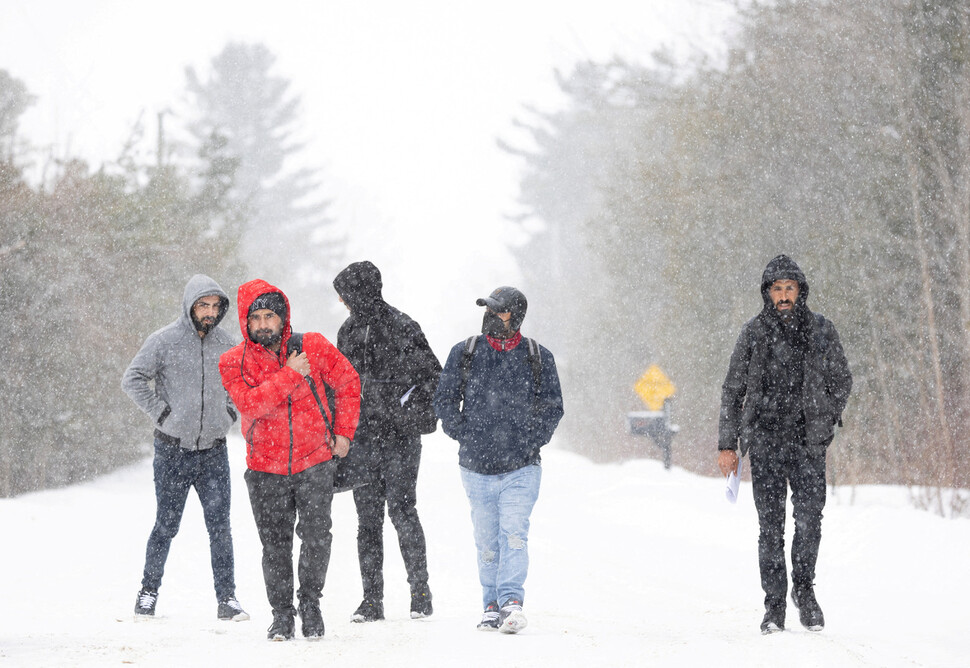 2월28일(현지시각) 튀르키예에서 온 난민신청자들이 미국 뉴욕주 섐플레인에서 캐나다로 향하는 ‘록샴로드’를 걷고 있다. 섐플레인/로이터 연합뉴스