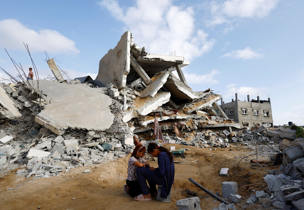 2024년 4월21일 팔레스타인 땅 가자지구 최남단 라파에서 이스라엘군의 공습으로 무너져내린 건물 앞에 두 어린이가 고개를 숙인 채 앉아 있다. REUTERS