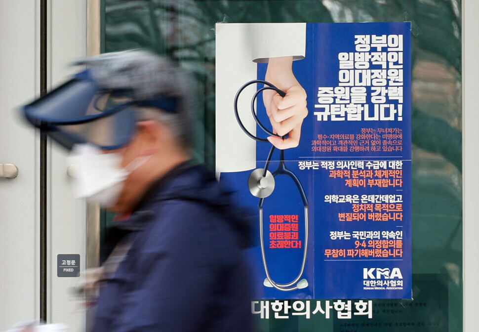A person passes by the Korean Medical Association’s headquarters in Yongsan District, Seoul, on Feb. 6, where a poster on the door condemns the administration’s “unilateral” increase to the medical school admission cap. (Yonhap)