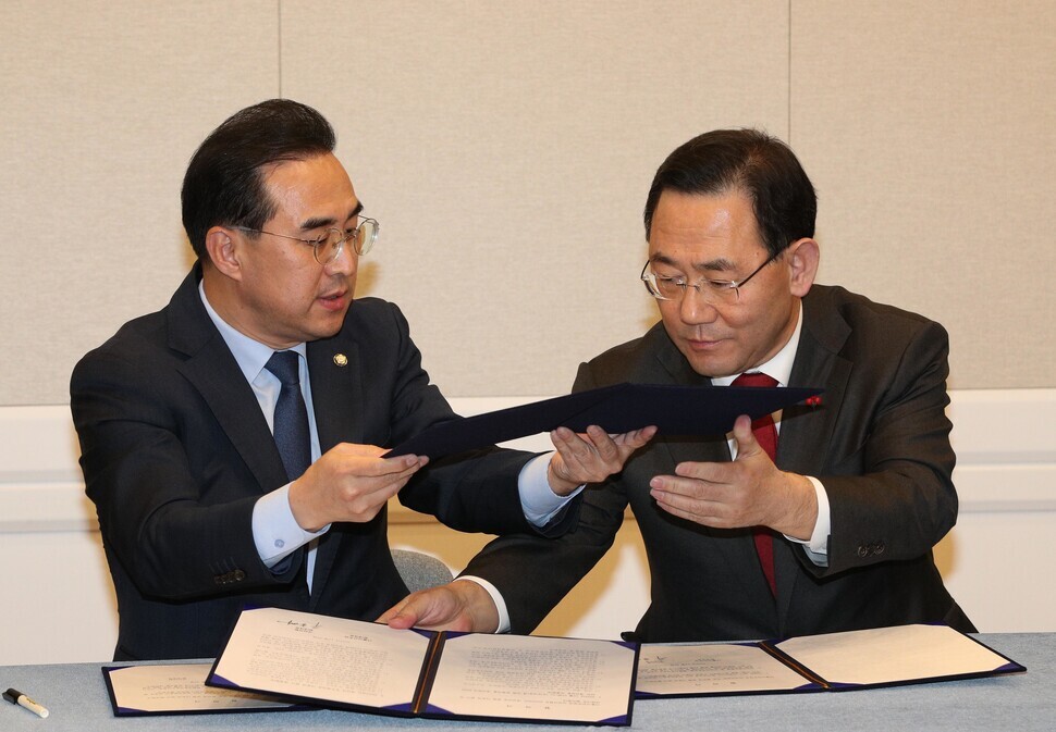 Democratic Party floor leader Park Hong-keun (left) and People Power Party floor leader Joo Ho-young exchange forms of agreement on the bill for next year’s budget after signing them on Dec. 22. (Kim Bong-gyu/The Hankyoreh)