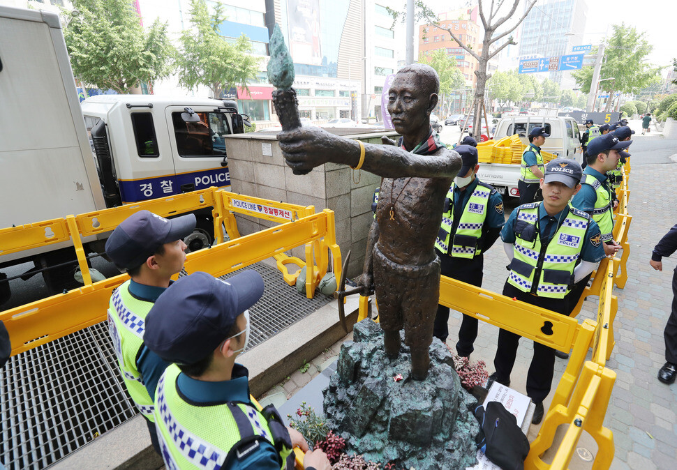 Police surround the statue of a Korean man forced into labor under imperial Japanese rule near a truck provided to remove the statue from the premises of the Japanese consulate in Busan’s Dong district on May 31. Nearby