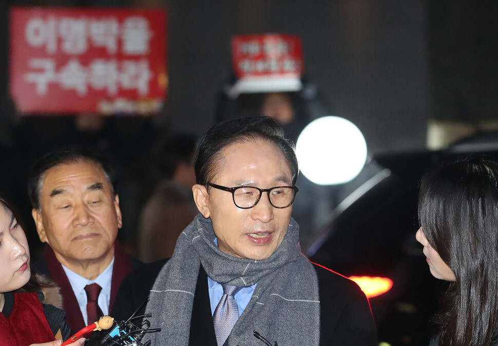 Former President Lee Myung-bak stops to answer a reporter’s question on his way to a year-end party at a restaurant in the Gangnam district of Seoul on Dec. 18. Behind him