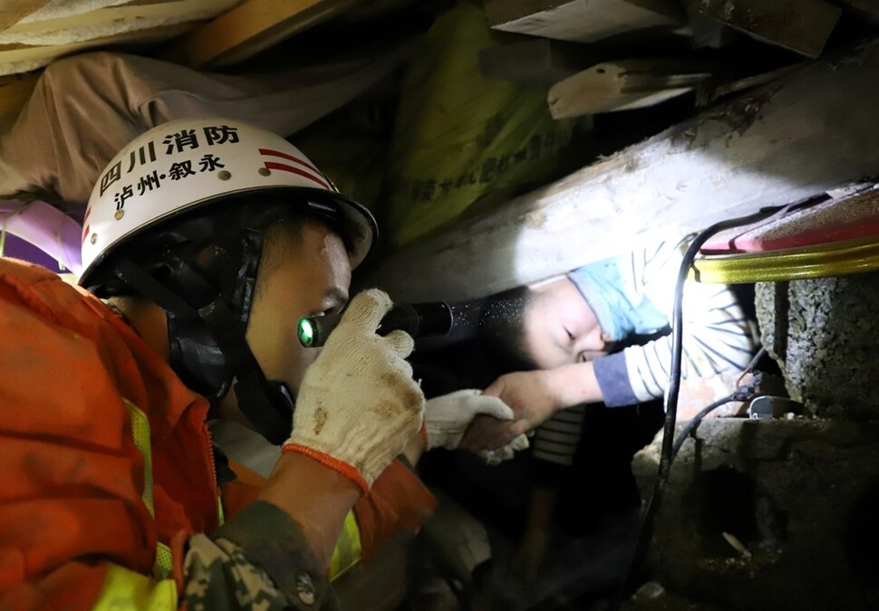 중국 쓰촨성 쉬융 마을 산사태 현장에서 12월9일 한 소년을 소방대원이 구조하고 있다.
