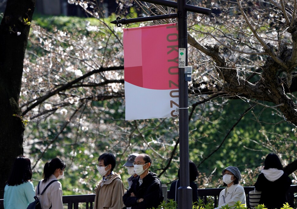 2020년 3월 일본 정부가 ‘2020 도쿄올림픽’ 연기를 발표한 가운데 도쿄 시민들이 마스크를 쓰고 벚꽃 구경을 나온 공원에 올림픽 홍보 깃발이 걸려 있다. REUTERS 연합뉴스