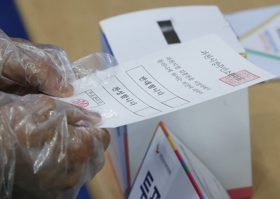 김종천 경기도 과천시장에 대한 주민소환 투표가 진행 중인 30일 오후 과천시 부림동 주민센터에 설치된 투표소에서 유권자가 투표용지를 받고 있다. 연합뉴스.