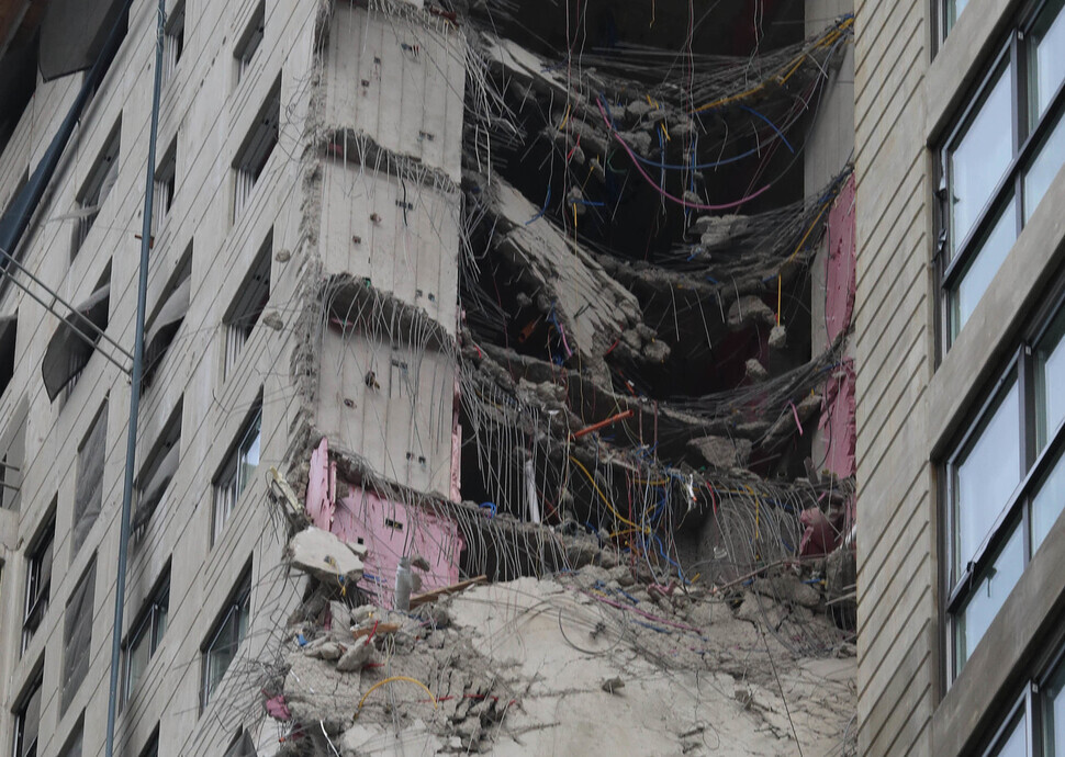 Rebar and other rubble hang from the side of the partially collapsed outer wall of an apartment building under construction in western Gwangju’s Seo District on Wednesday. (Shin So-young/The Hankyoreh)